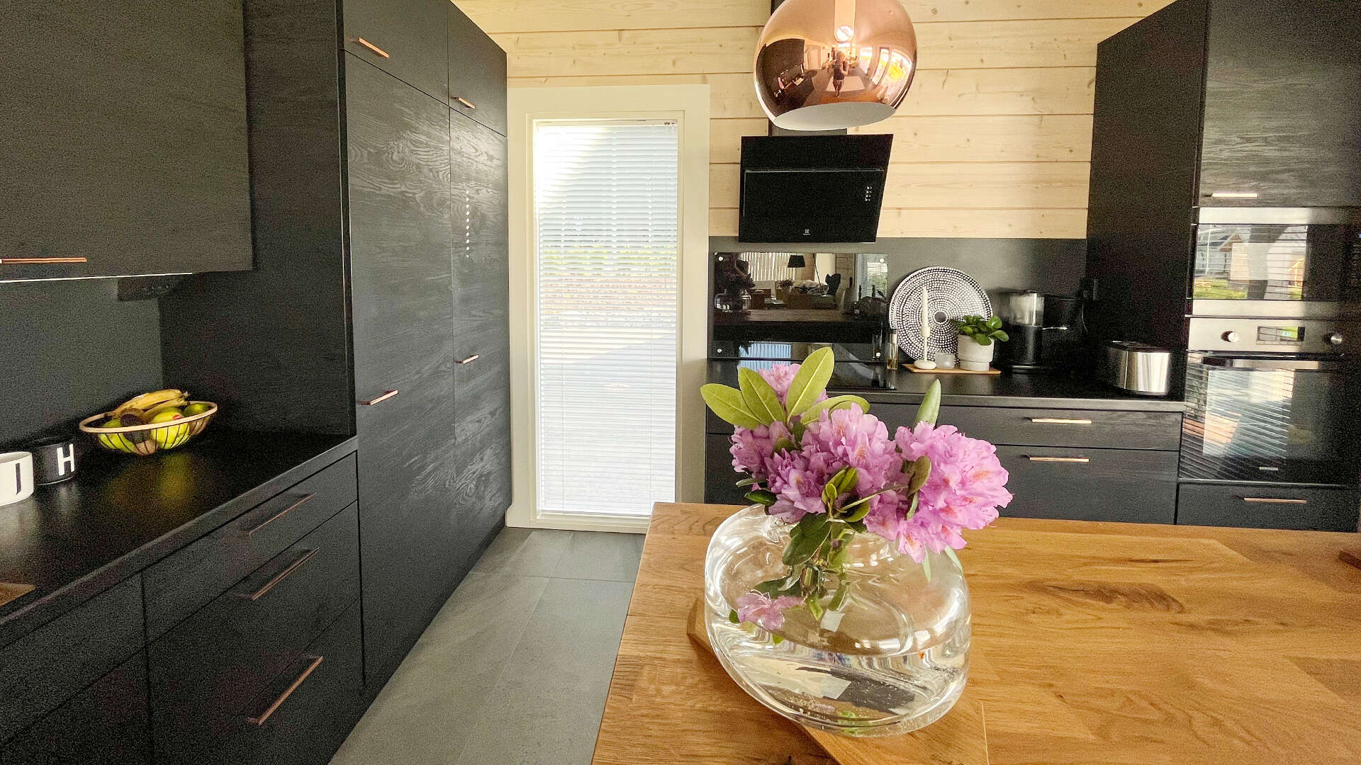 The black cupboards, lightly coloured walls, and the roomy top of the kitchen create a cosy atmosphere. 
