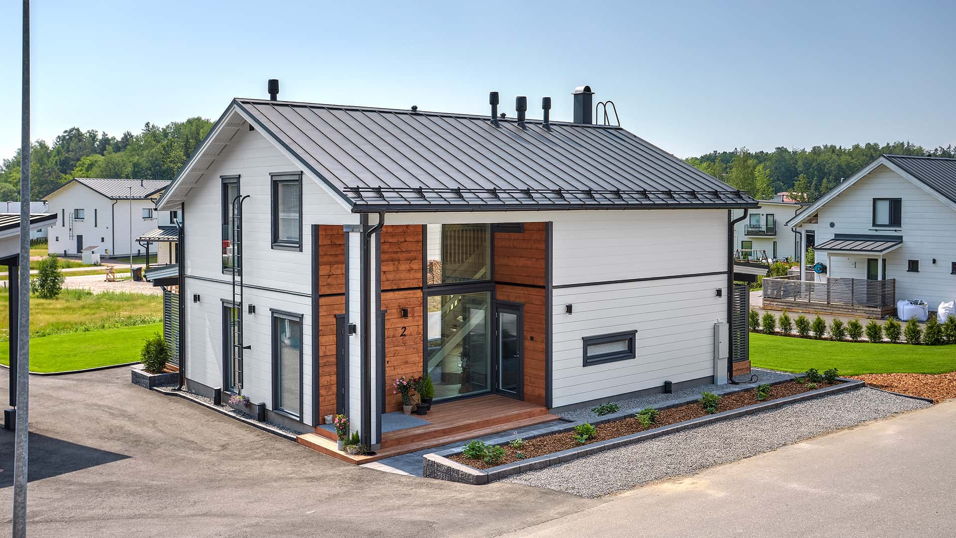 Experiences of living in a log home: the main entrance A white two-storey log house with a gabled roof and an indented entrance. Black windows, doors, and covering boards give the house a contrasted look.