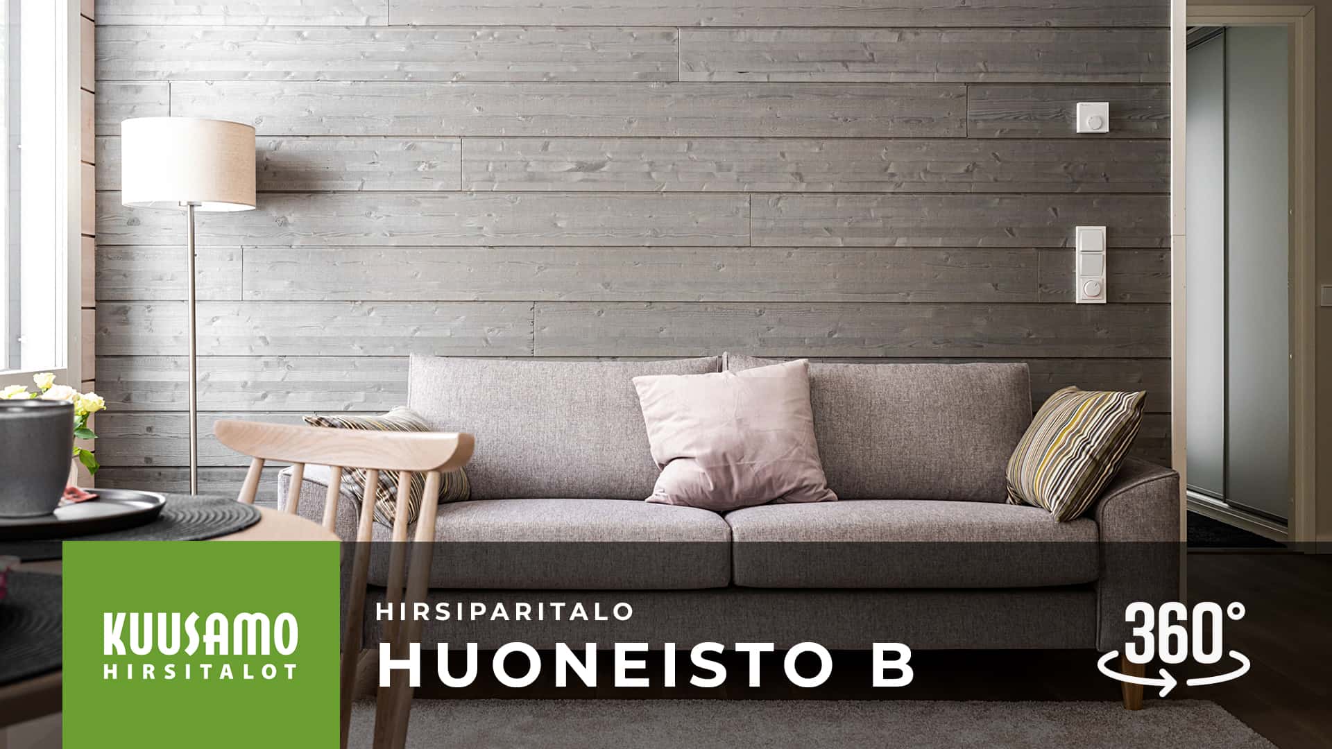 Hirsiparitalon B-huoneiston oleskelutilassa on upea harmaa paneelitehosteseinä, jonka edessä on kolmen hengen sohva. 