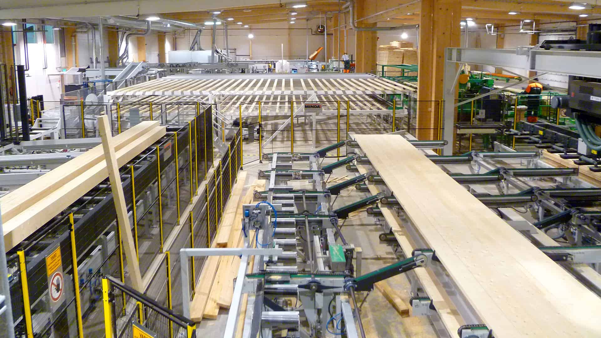 Raw materials entering the line for gluing and then compression. After the glue is applied, the laminated log needs to be under compression in ten minutes.