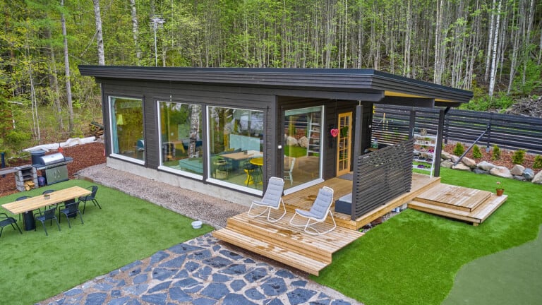 Holiday Home Piste 50, photographed from slightly higher up. The log building is painted dark. The cabin has a pent roof.