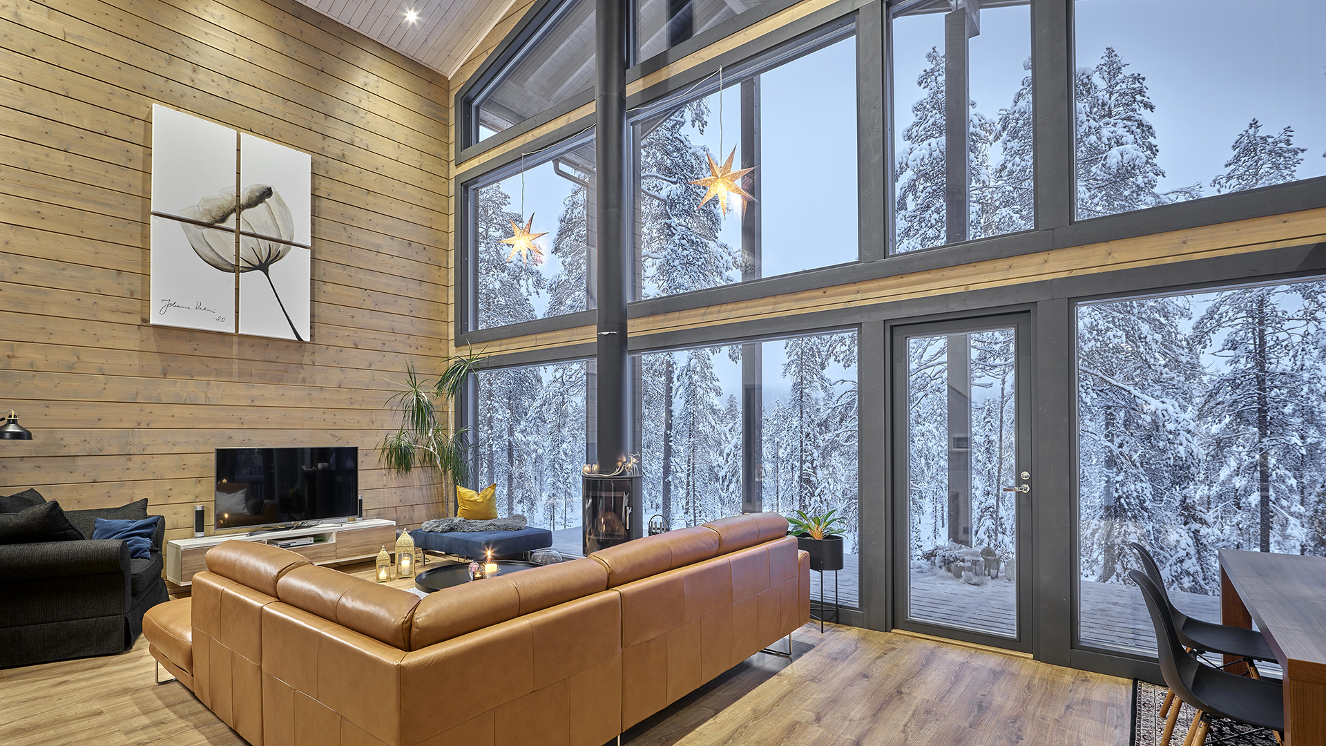 Hirsikodin korkea olohuone josta avautuu suuret ikkunat Rukan lumiseen luontoon päin.