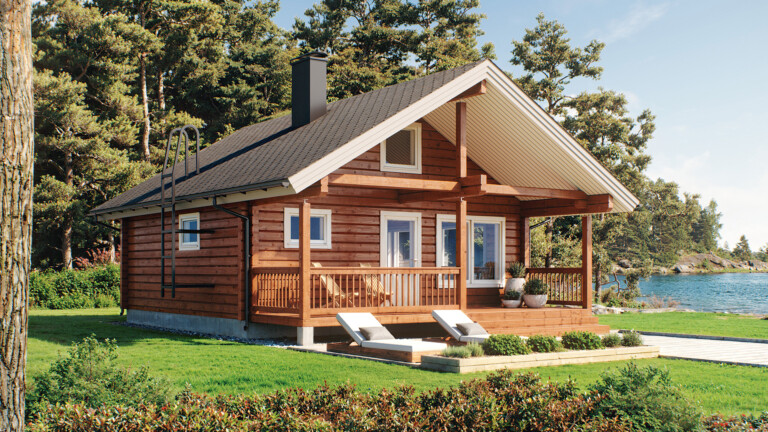 Harjakattoinen hirsimökki järven rannalla.