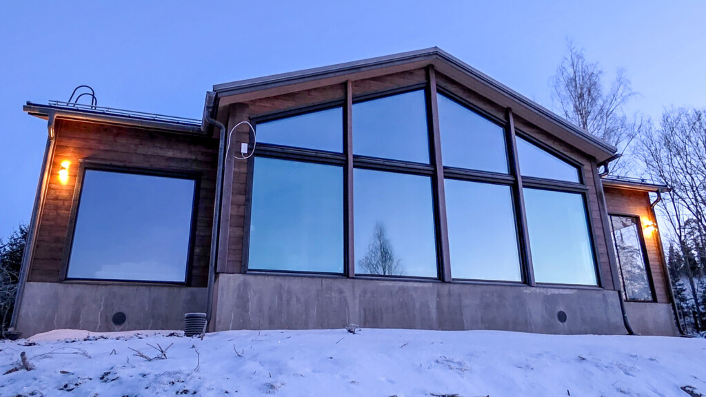 Hirsitalon takaosa isoine ikkunoineen talvisena iltana.